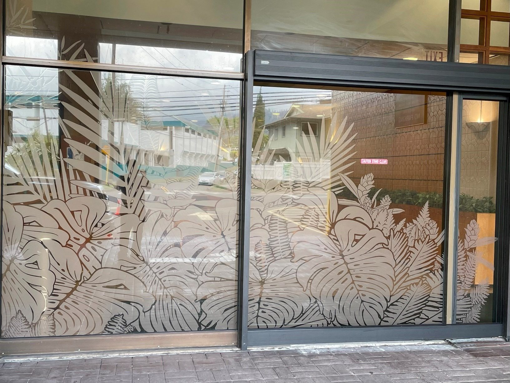 A Glass Door Featuring An Intricate Tropical Design, Showcasing Vibrant Leaves And Flowers.